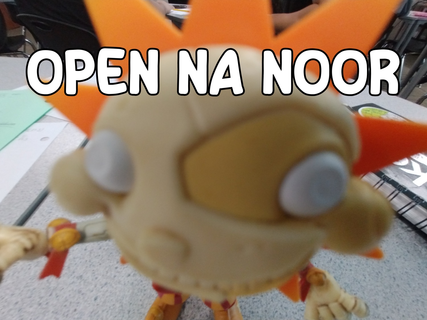 Cartoon toy figure pressed against the camera under 'OPEN NA NOOR'