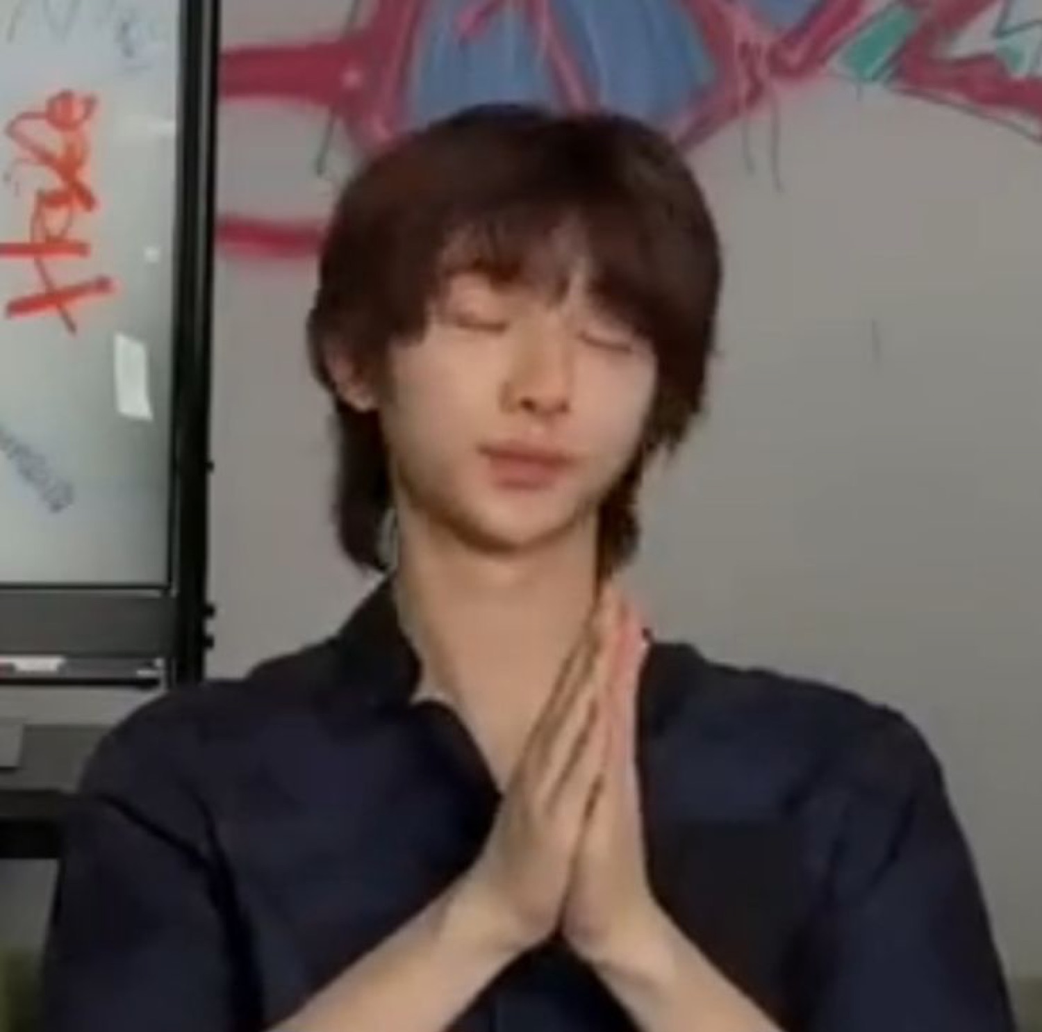 Young man with eyes closed and palms pressed together as if praying