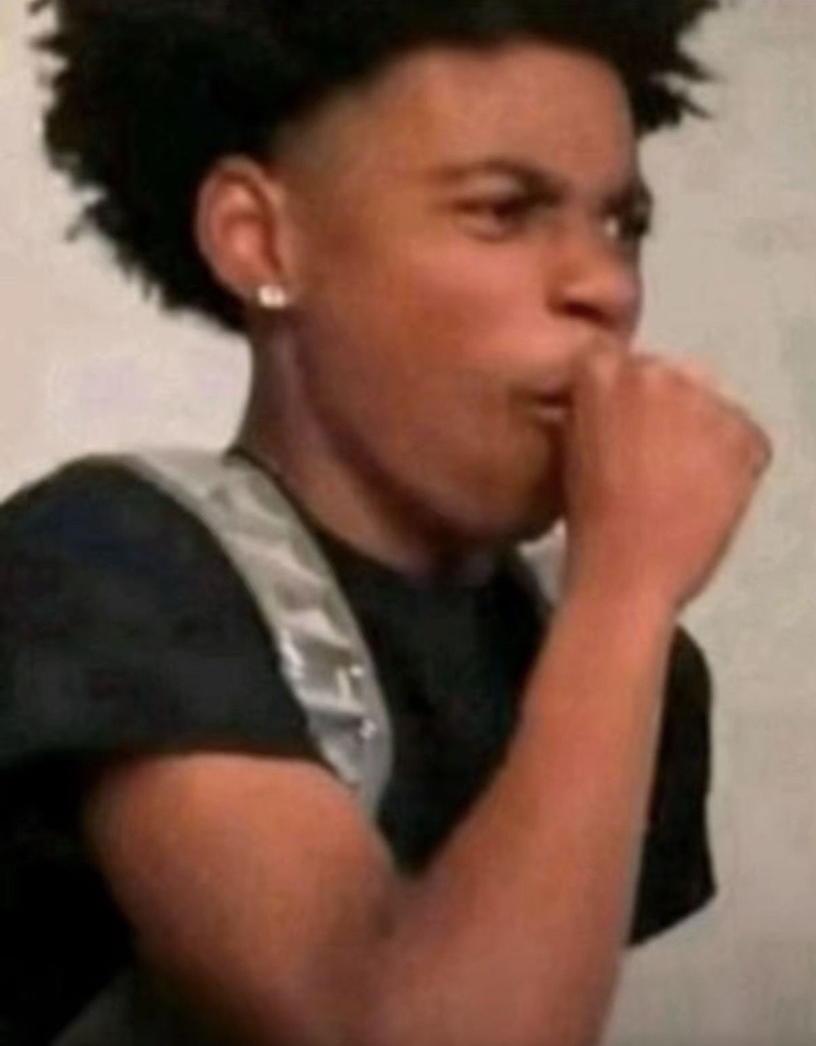 Guy with an afro pressing a fist to his mouth, trying hard to hold something in