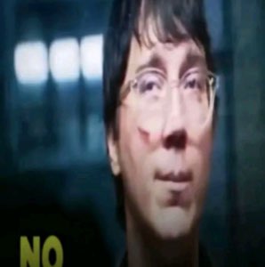 Blurry distorted man in glasses staring flatly with 'NO' in the corner