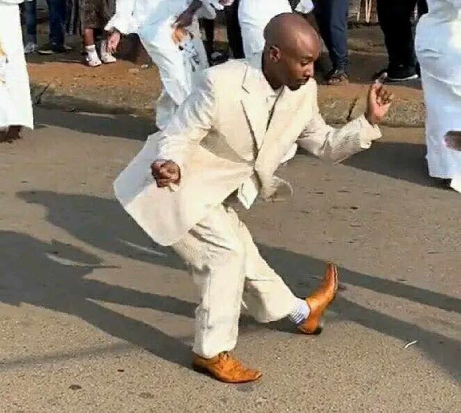 Man in a white suit busting a dance move in the street