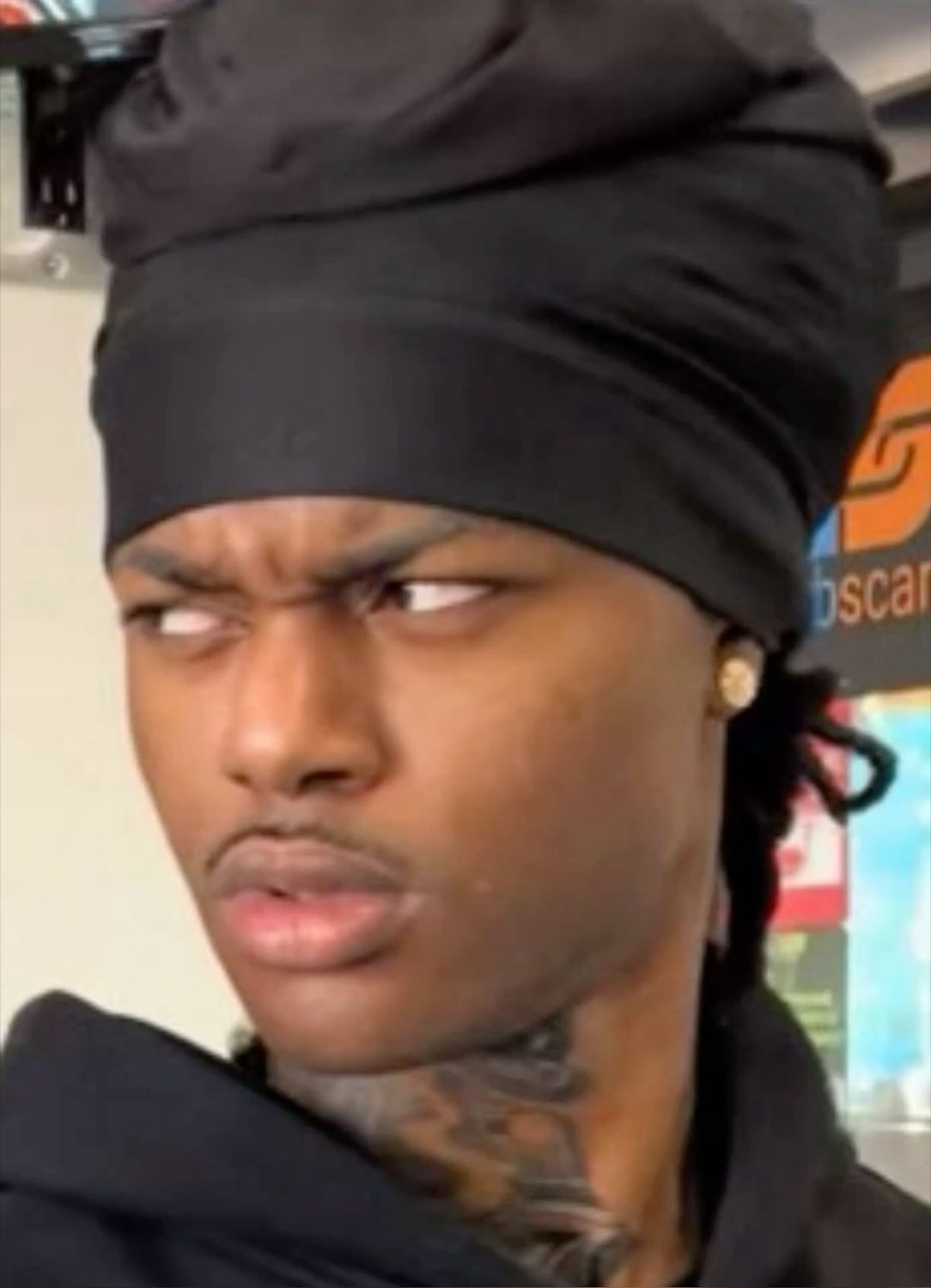 Man in a durag cutting a hard suspicious side-eye off to the corner