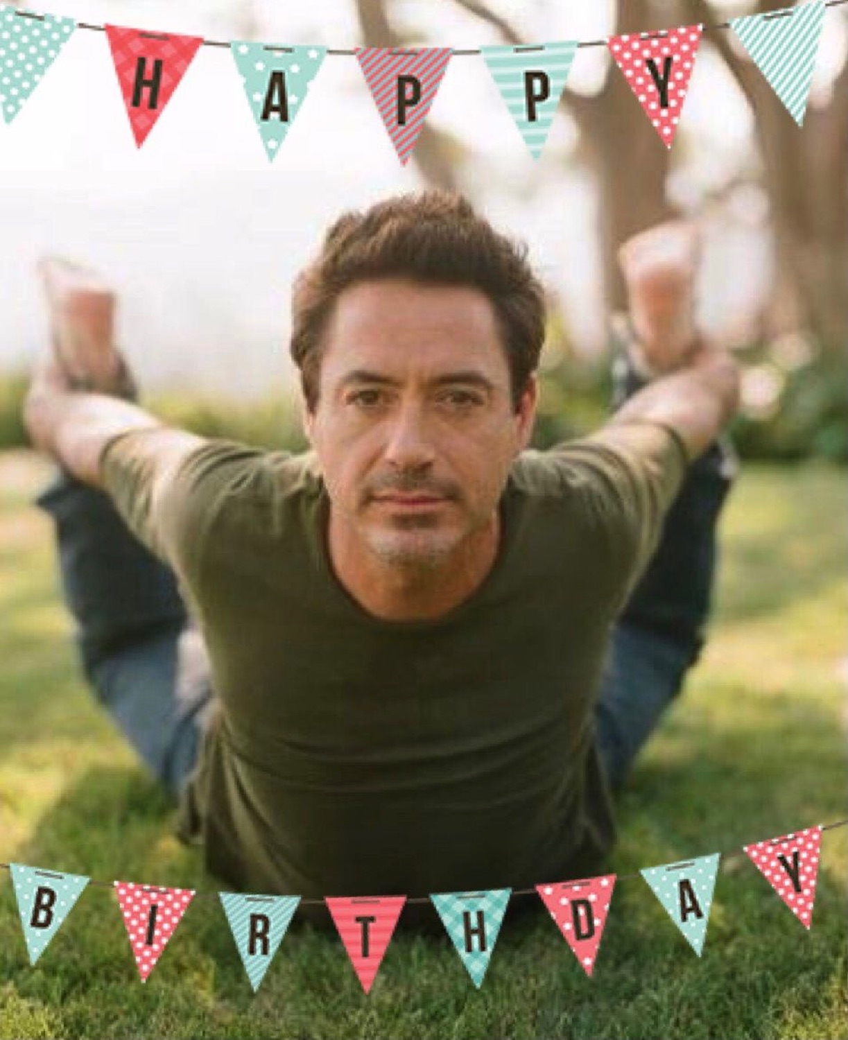Robert Downey Jr. doing a yoga stretch on the grass under HAPPY BIRTHDAY bunting