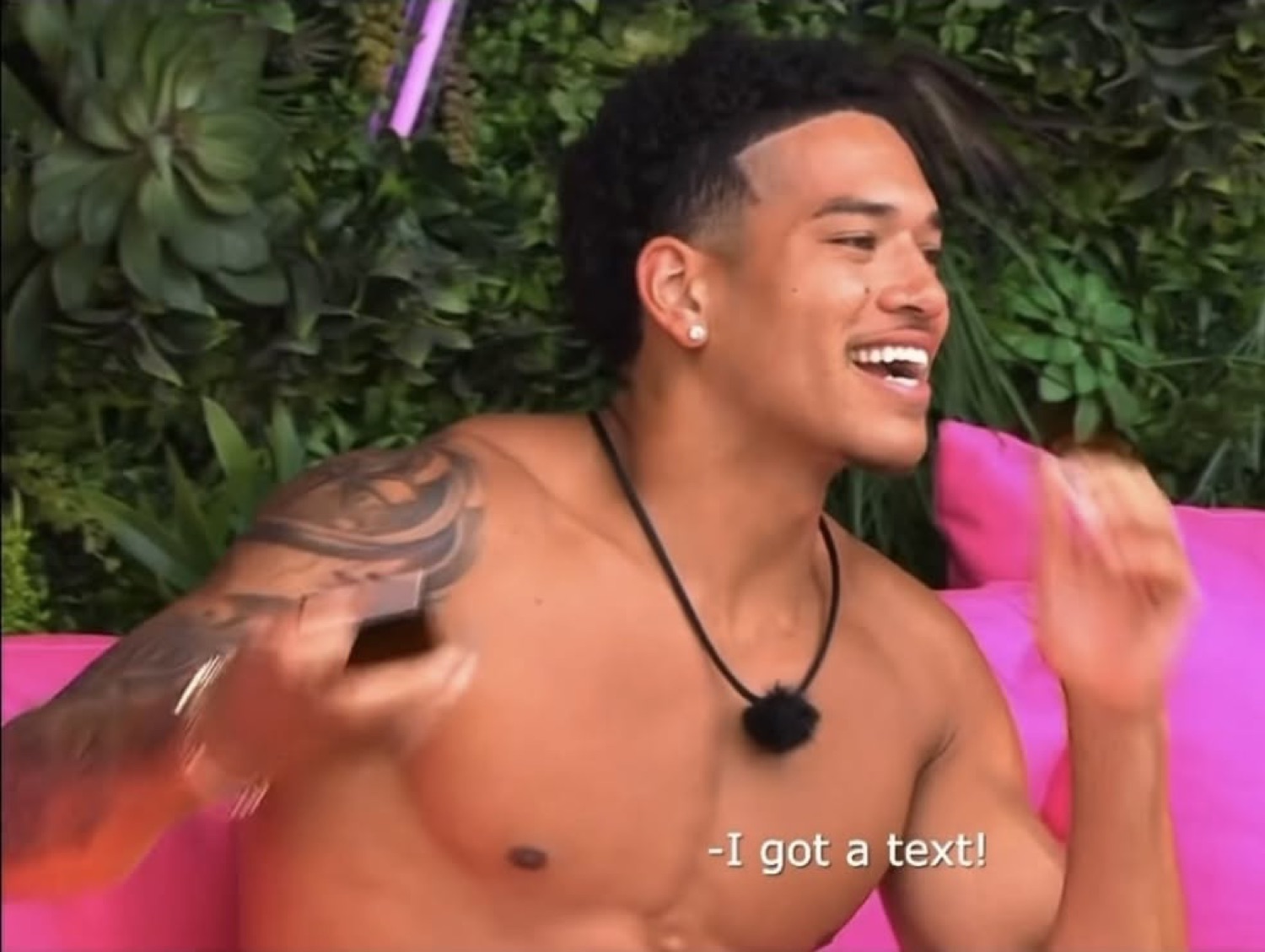 Love Island USA's Corbin laughing on a bean bag captioned '-I got a text!'
