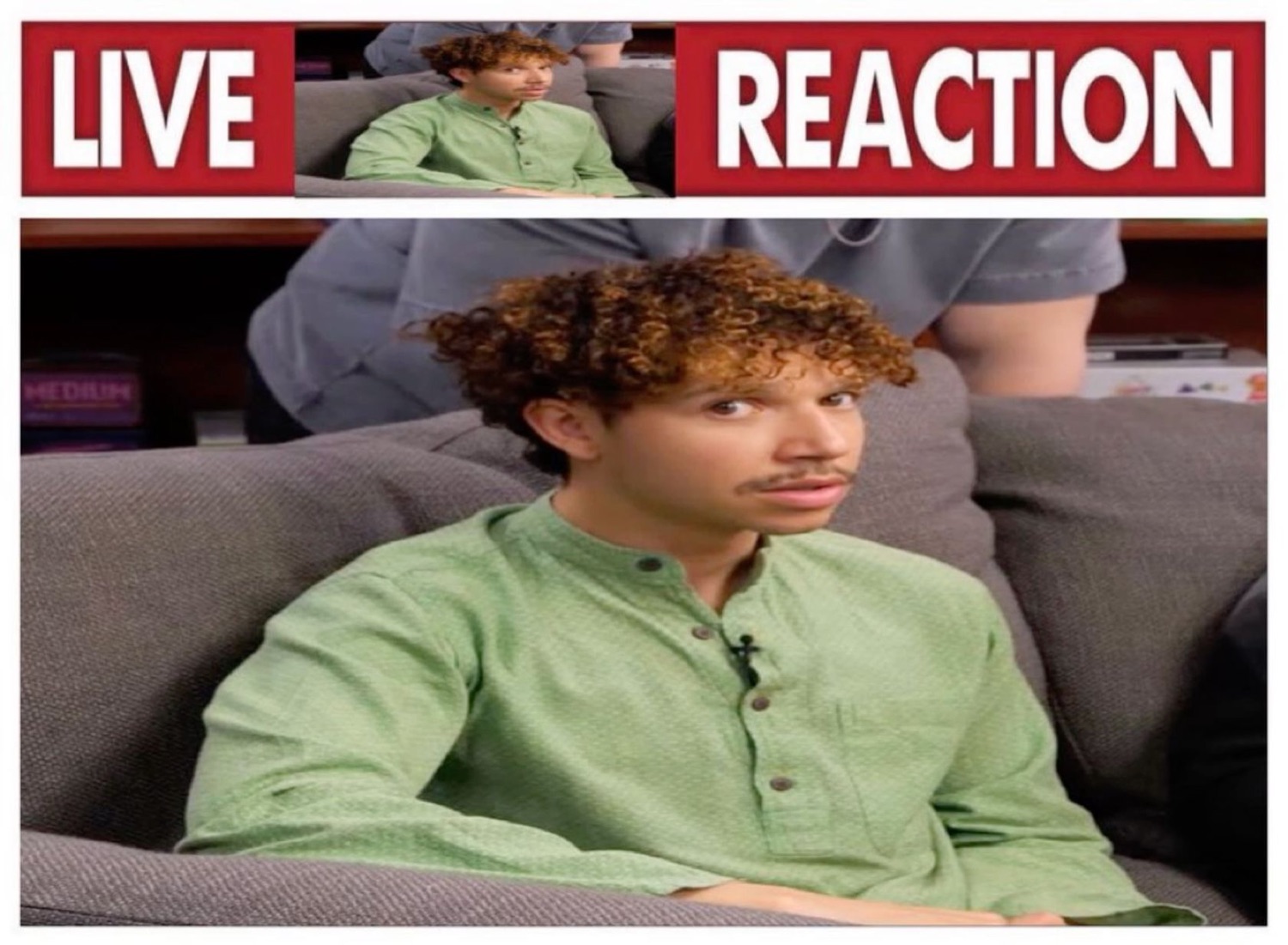 Curly-haired guy on a couch delivering a live reaction that is just complete unbothered flatness