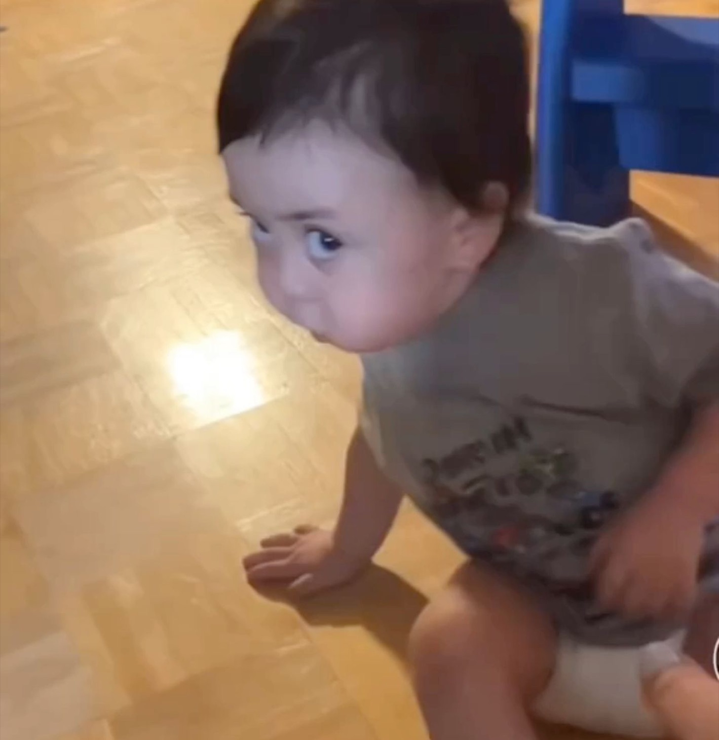 Baby on the floor resting its cheek down and shooting a flat, done side-eye