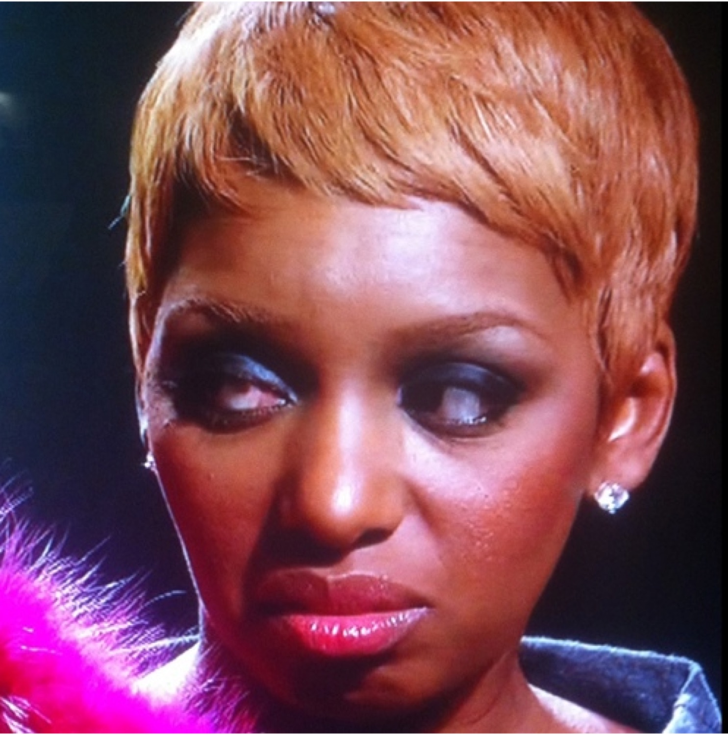 Woman with a short blonde pixie cut cutting a weary, unimpressed side-eye