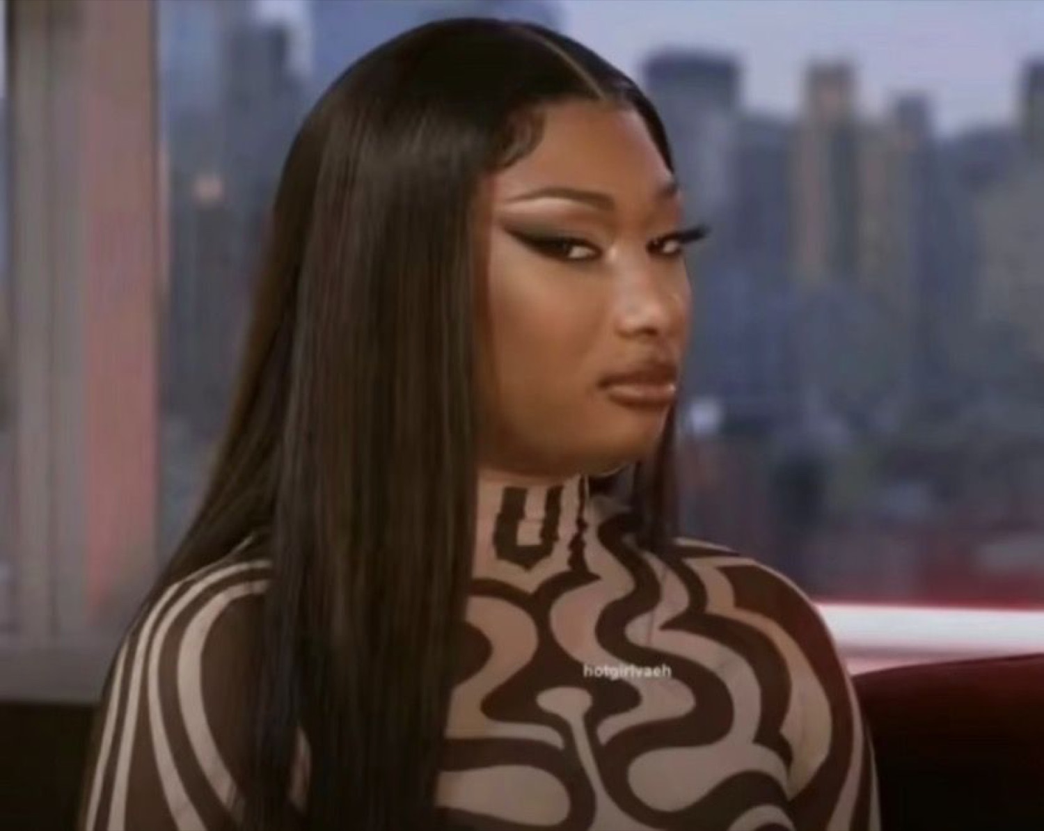 Megan Thee Stallion in a patterned bodysuit delivering a slow, withering side-eye during an interview