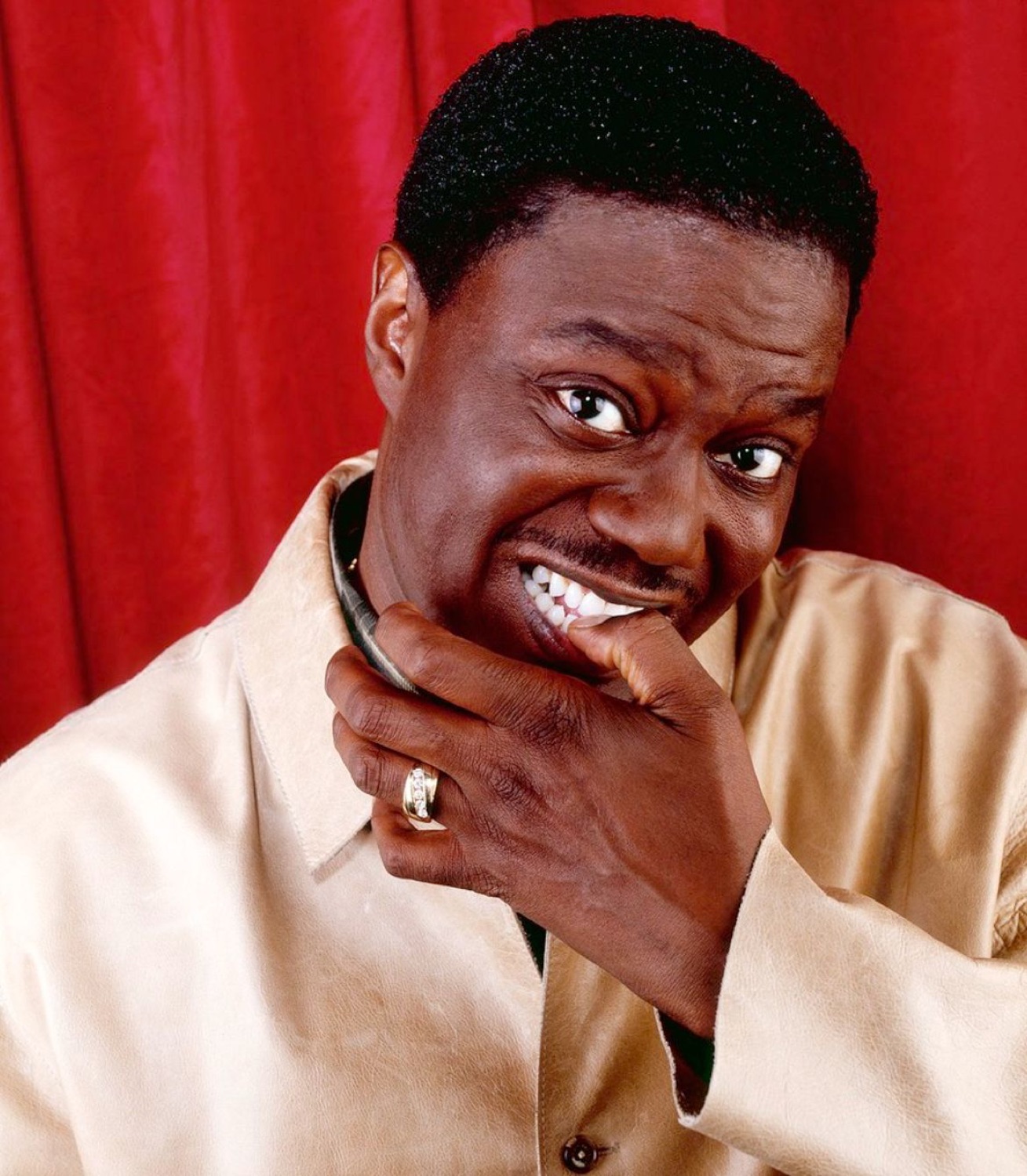 Bernie Mac grinning slyly with a hand on his chin