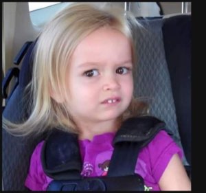 A blonde toddler in a car seat giving a skeptical, unimpressed side glance