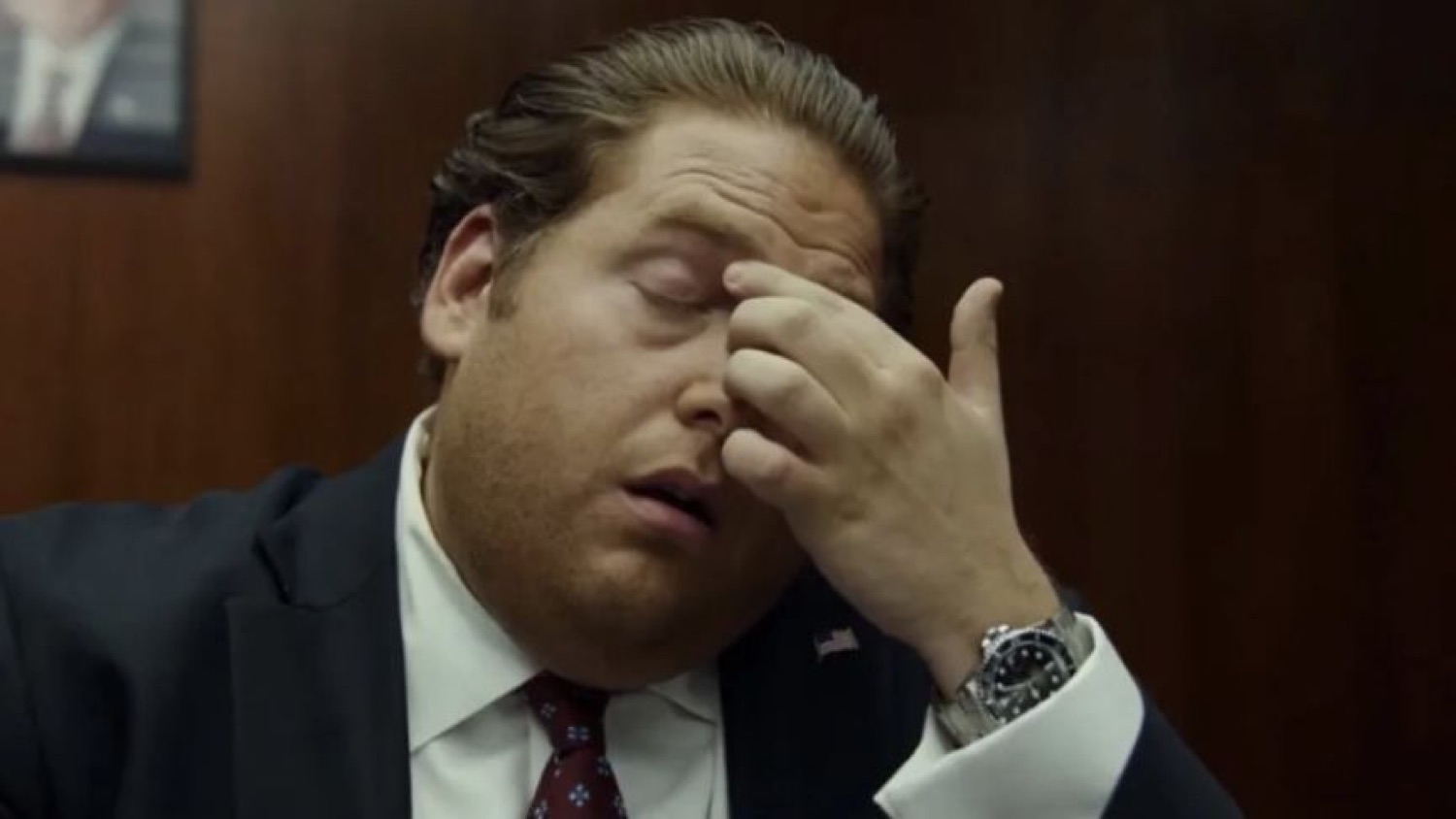 Man in a suit pinching the bridge of his nose in exhausted disbelief