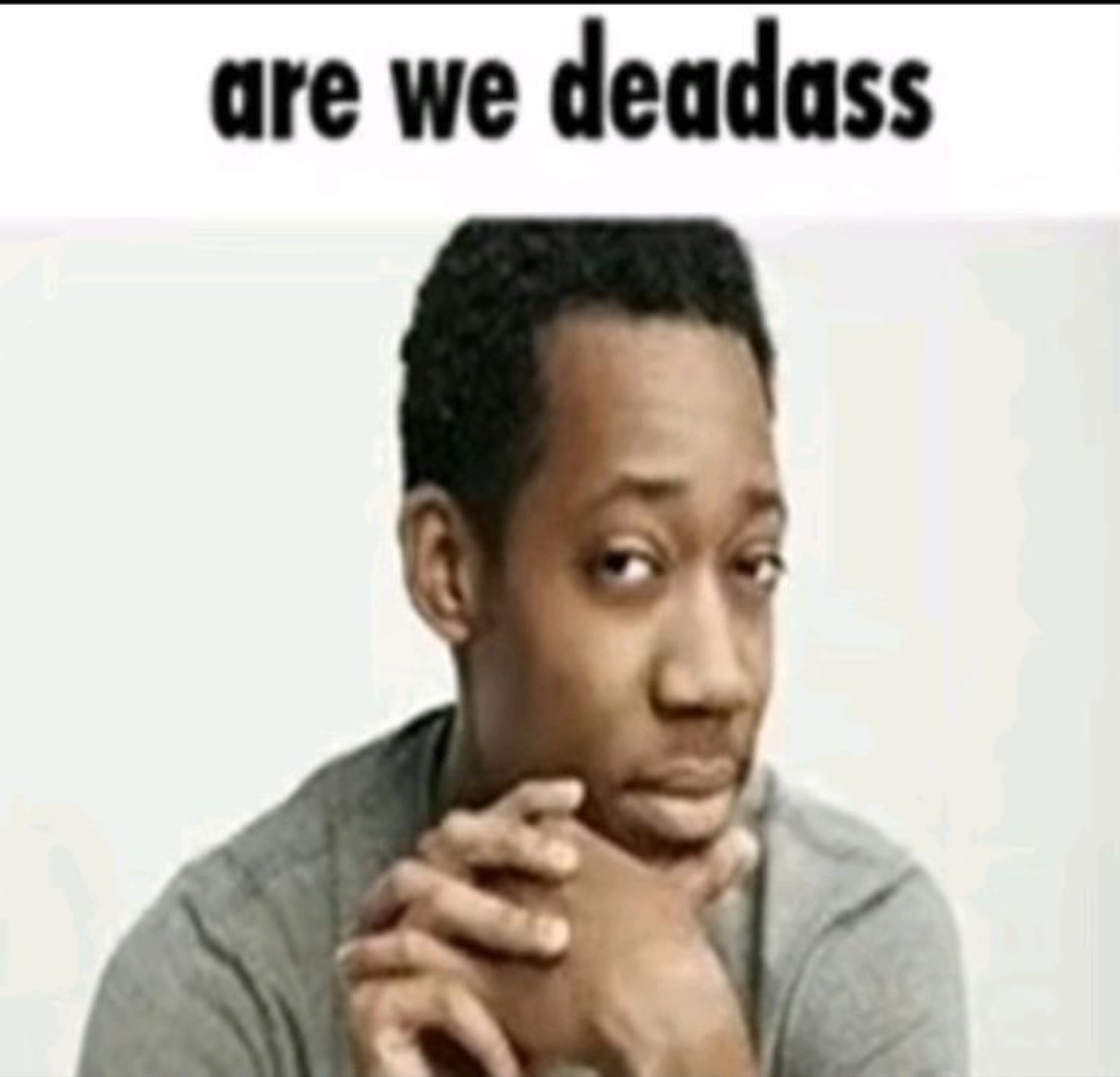 Man resting chin on clasped hands with a skeptical stare captioned 'are we deadass'