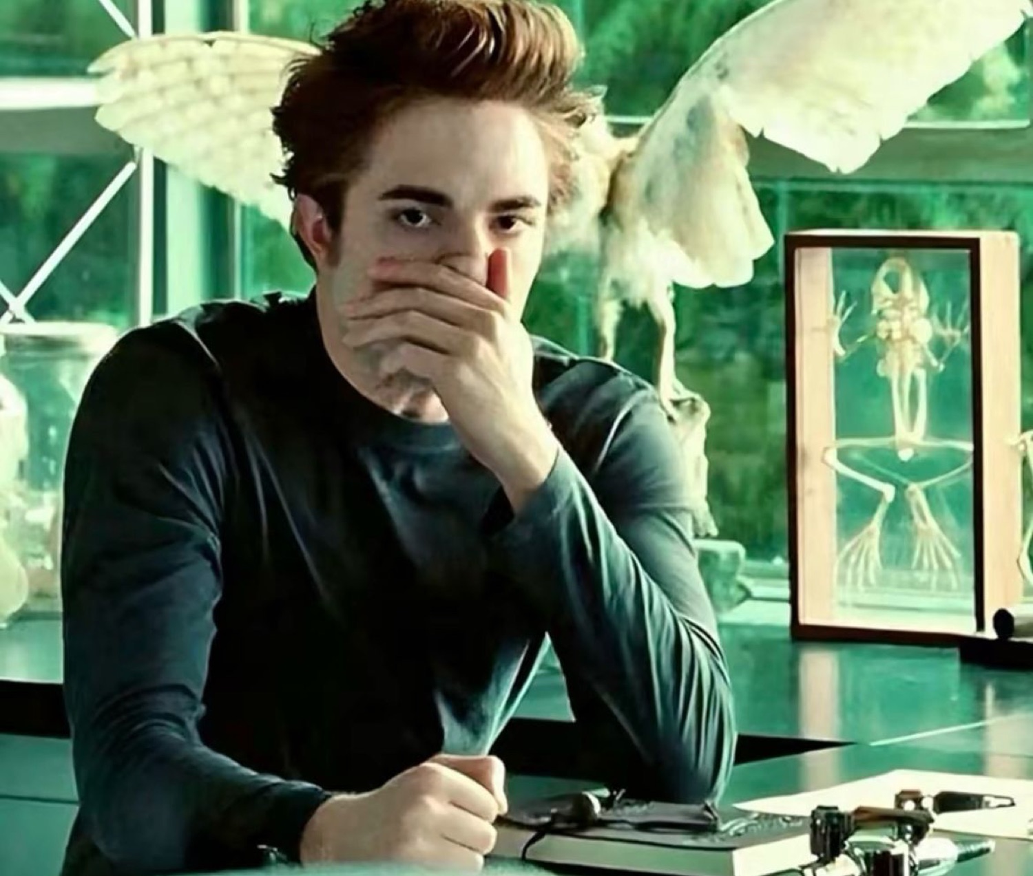 Pale young man in a lab covering his mouth with his hand, looking wide-eyed and stunned