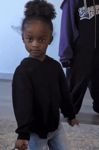 Little girl in a black sweatshirt doing a happy little dance