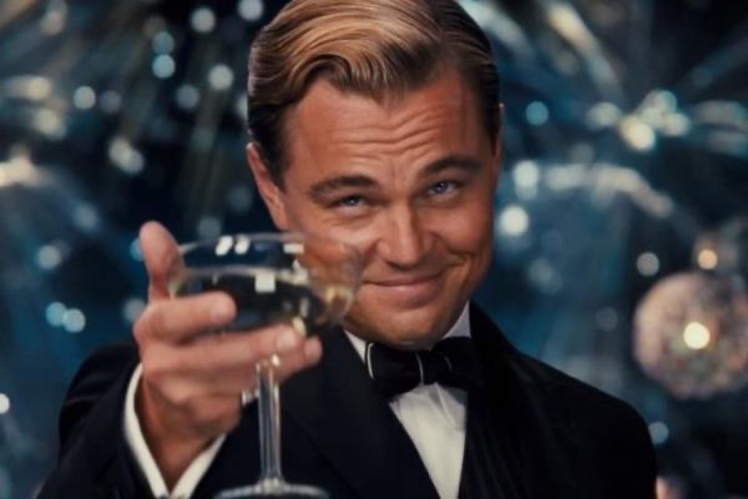 Leonardo DiCaprio as Gatsby raising a champagne glass with a smug smile