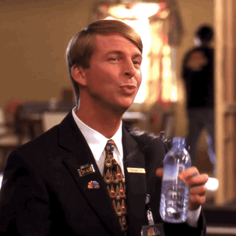 Jack McBrayer in a suit nervously chugging a bottle of water
