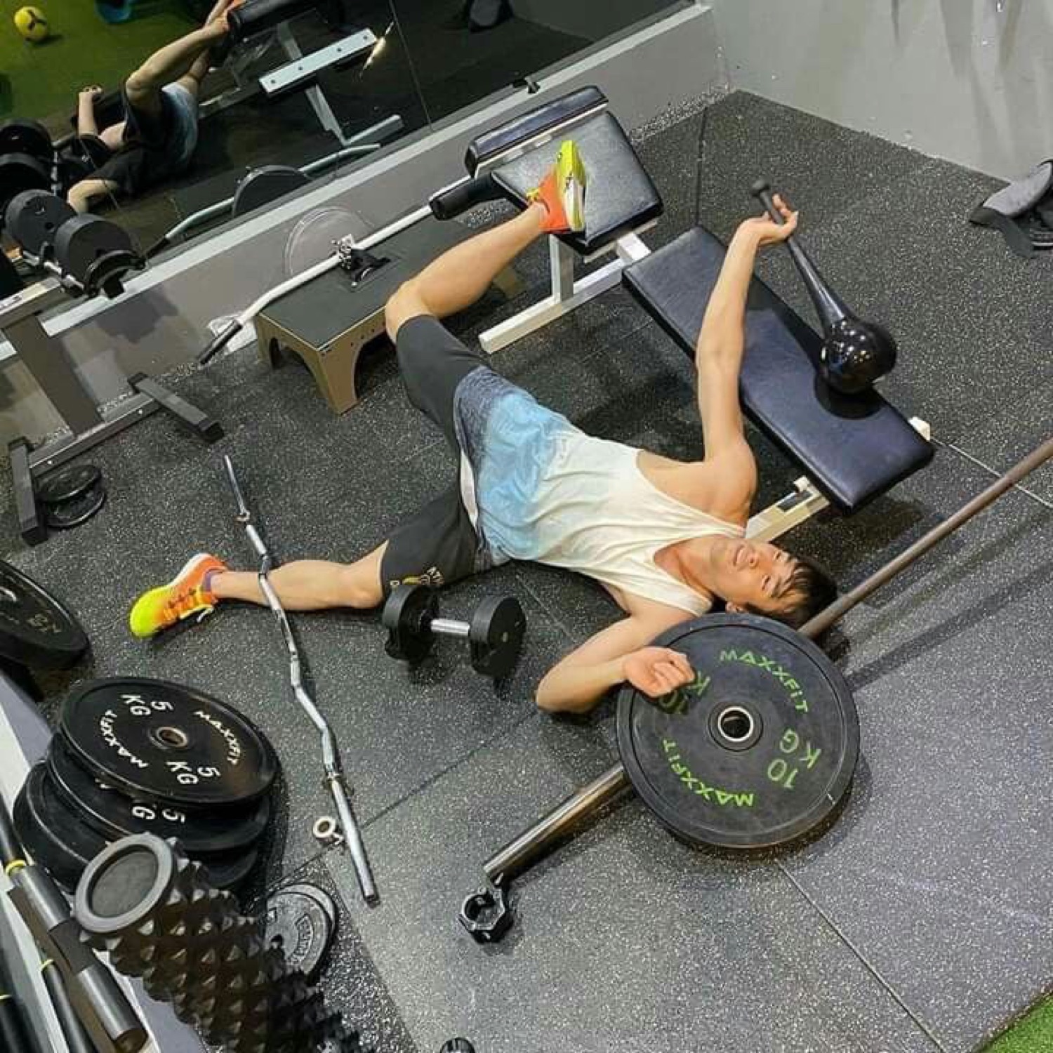 Guy sprawled on the gym floor after dropping a barbell