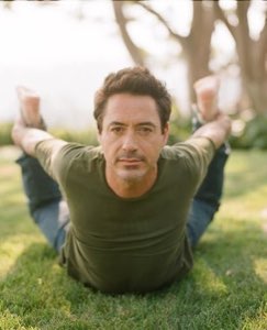 Robert Downey Jr. lying on grass gripping his own ankles with a deadpan stare