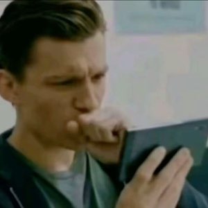 Tom Holland squinting nervously at a phone, trying to make sense of it
