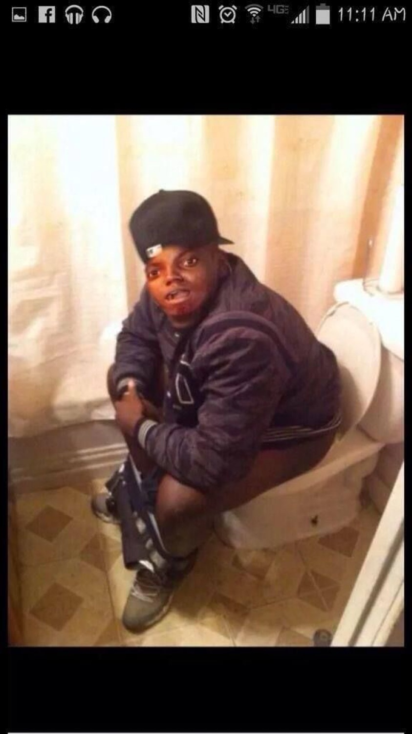 Guy sitting fully clothed on a toilet staring into the camera