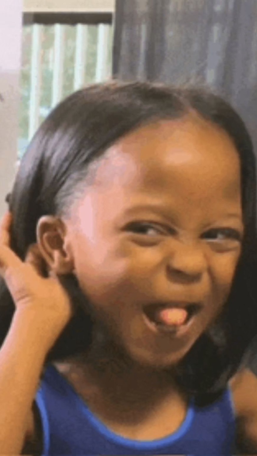 Little girl scrunching up her face in a gleeful, mischievous grimace