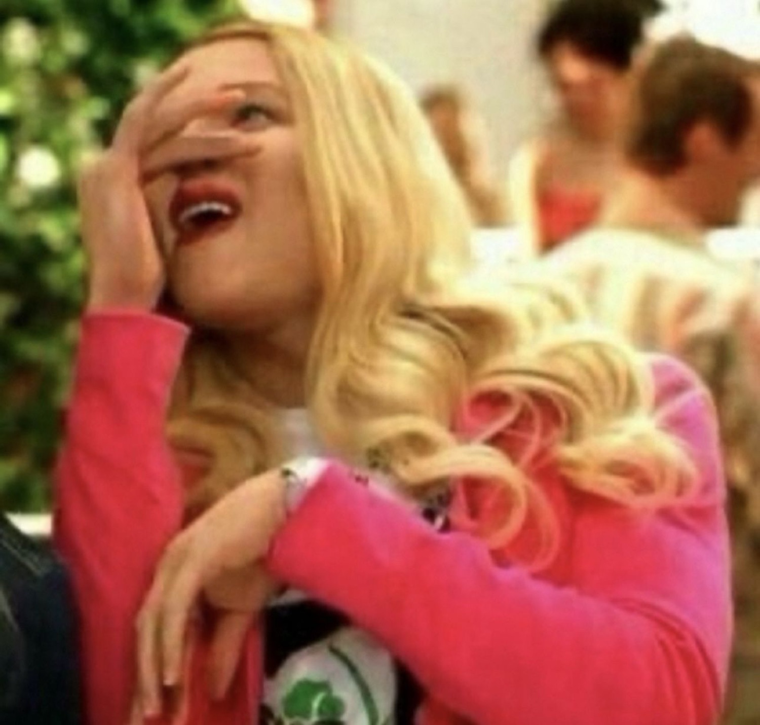 Blonde woman peeking through her fingers, laughing in disbelief