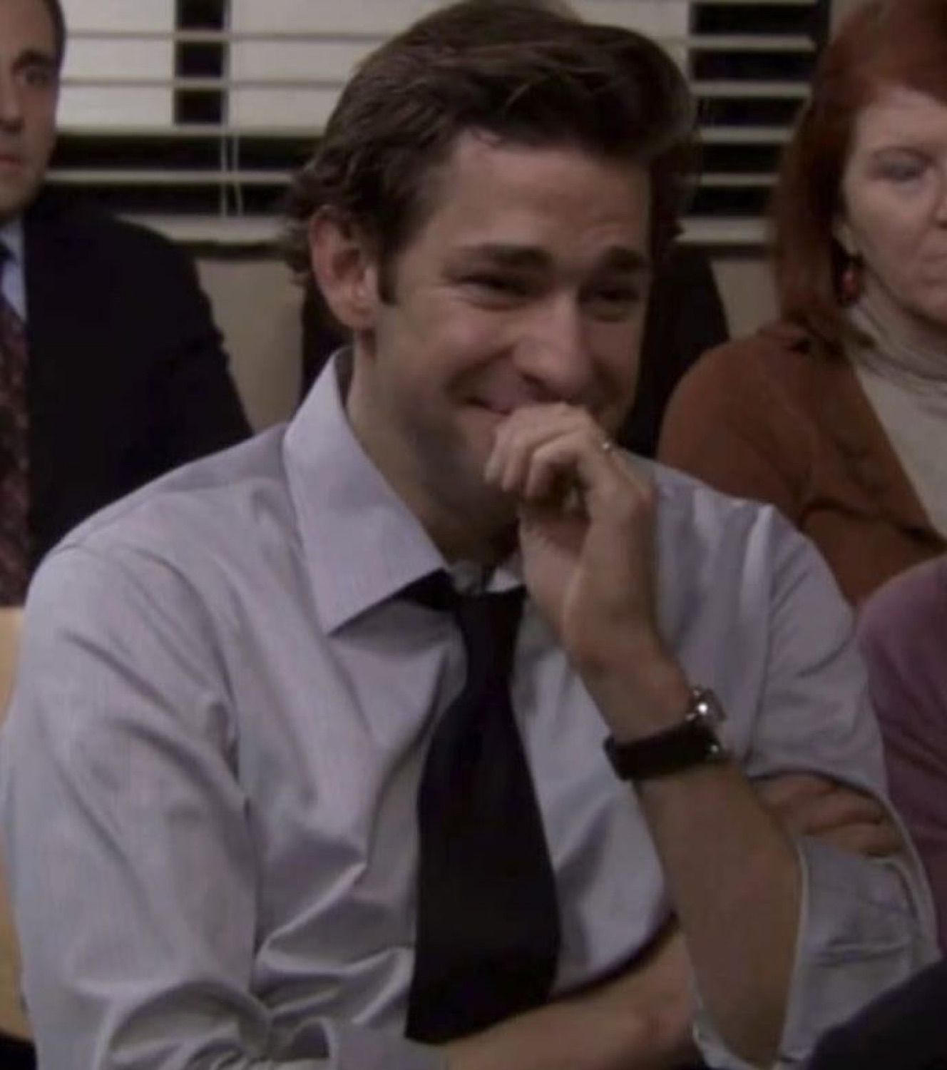 Man in office setting suppressing a laugh behind his hand, clearly losing it