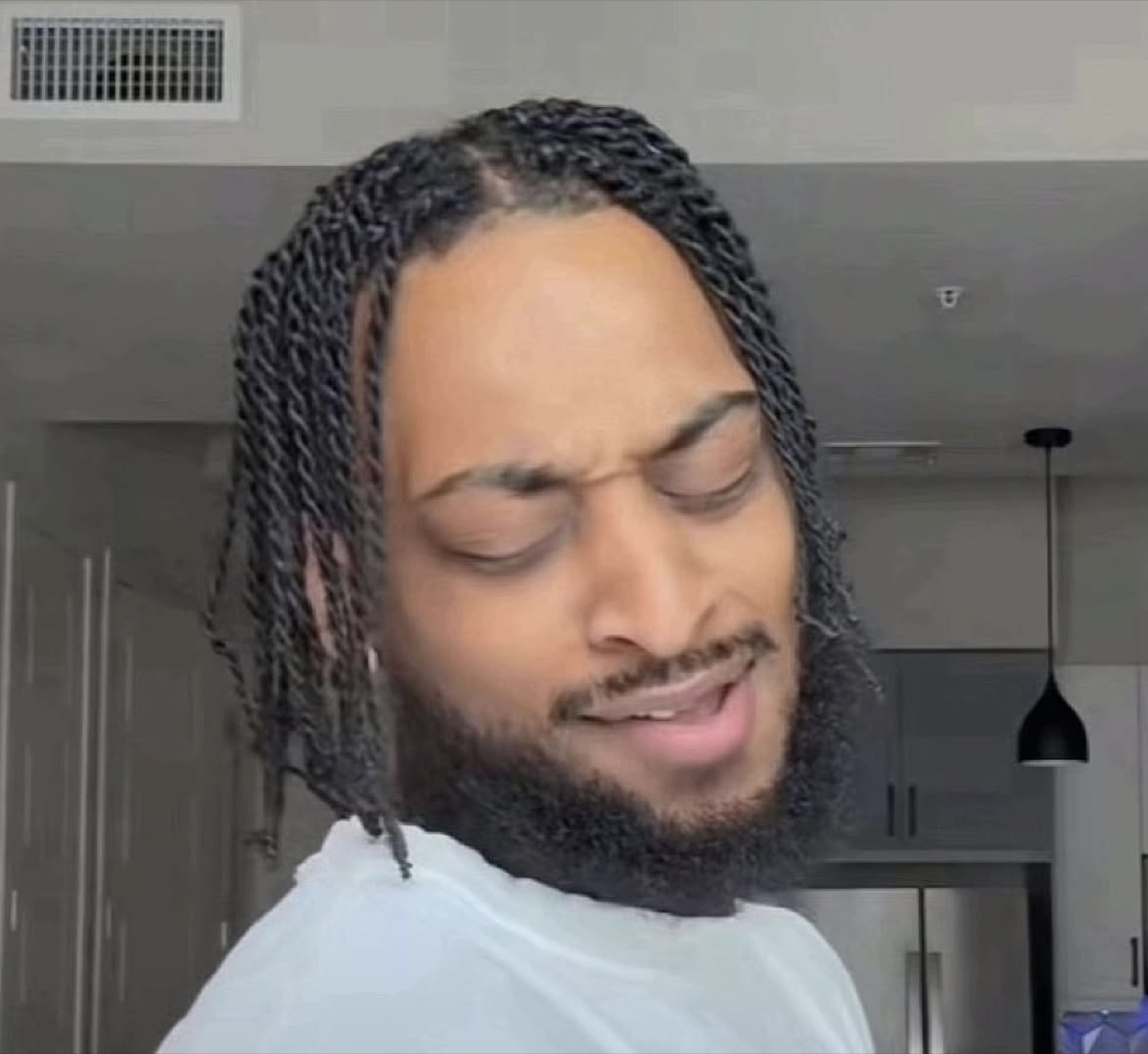 Man with braids glancing back over his shoulder with a disgusted, unimpressed grimace