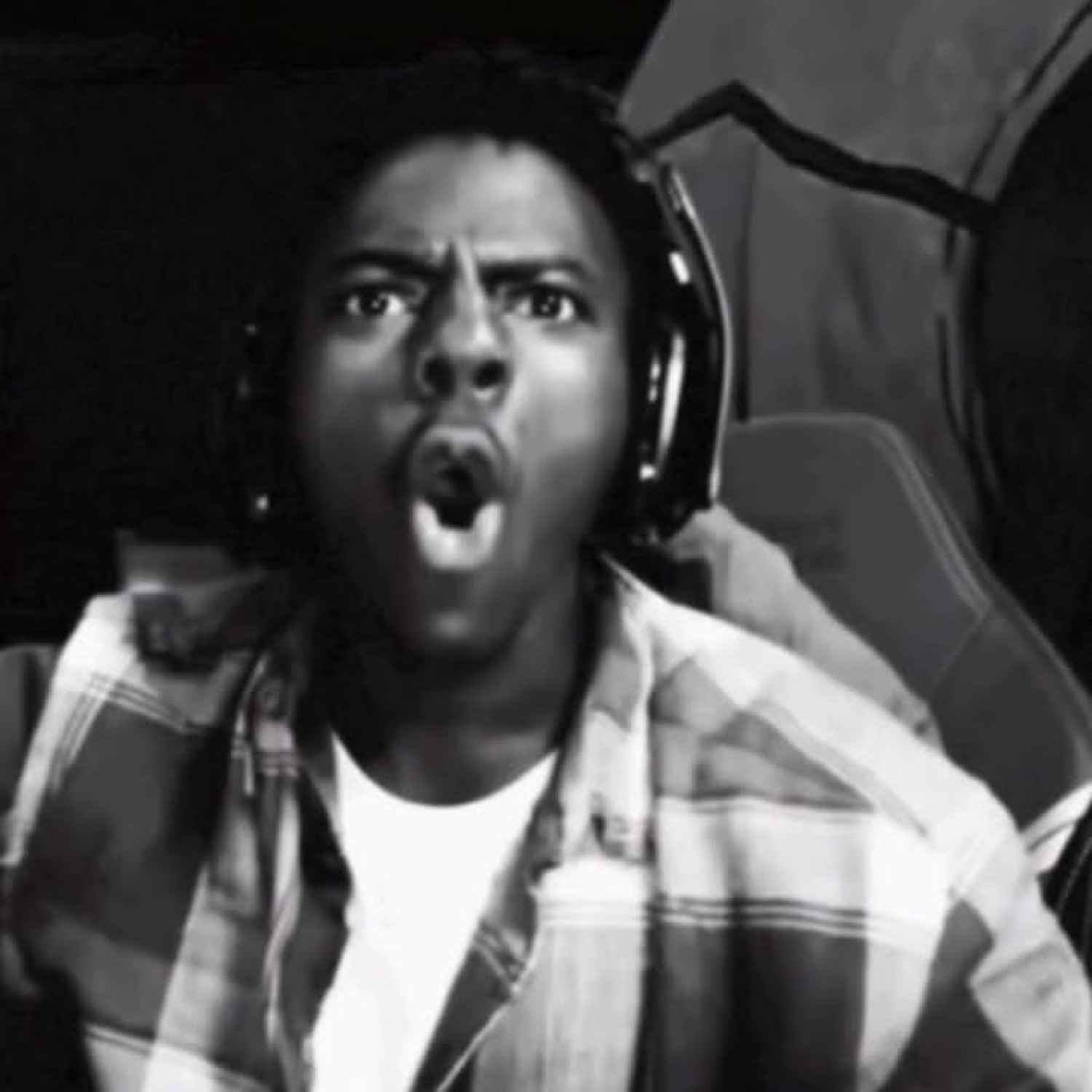 Guy in headphones at a gaming chair absolutely losing it with an open-mouth scream