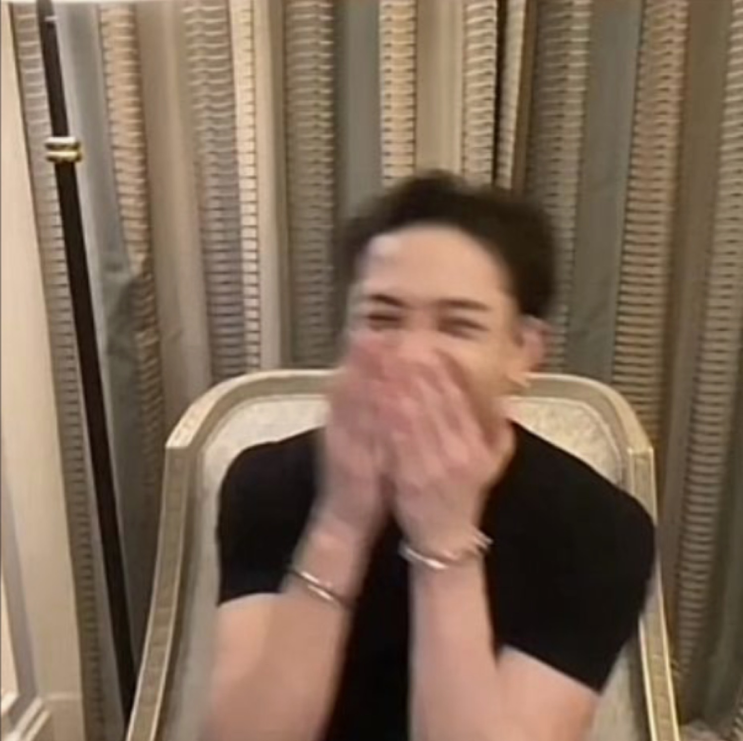 Guy covering his mouth with both hands while cracking up in a fancy chair