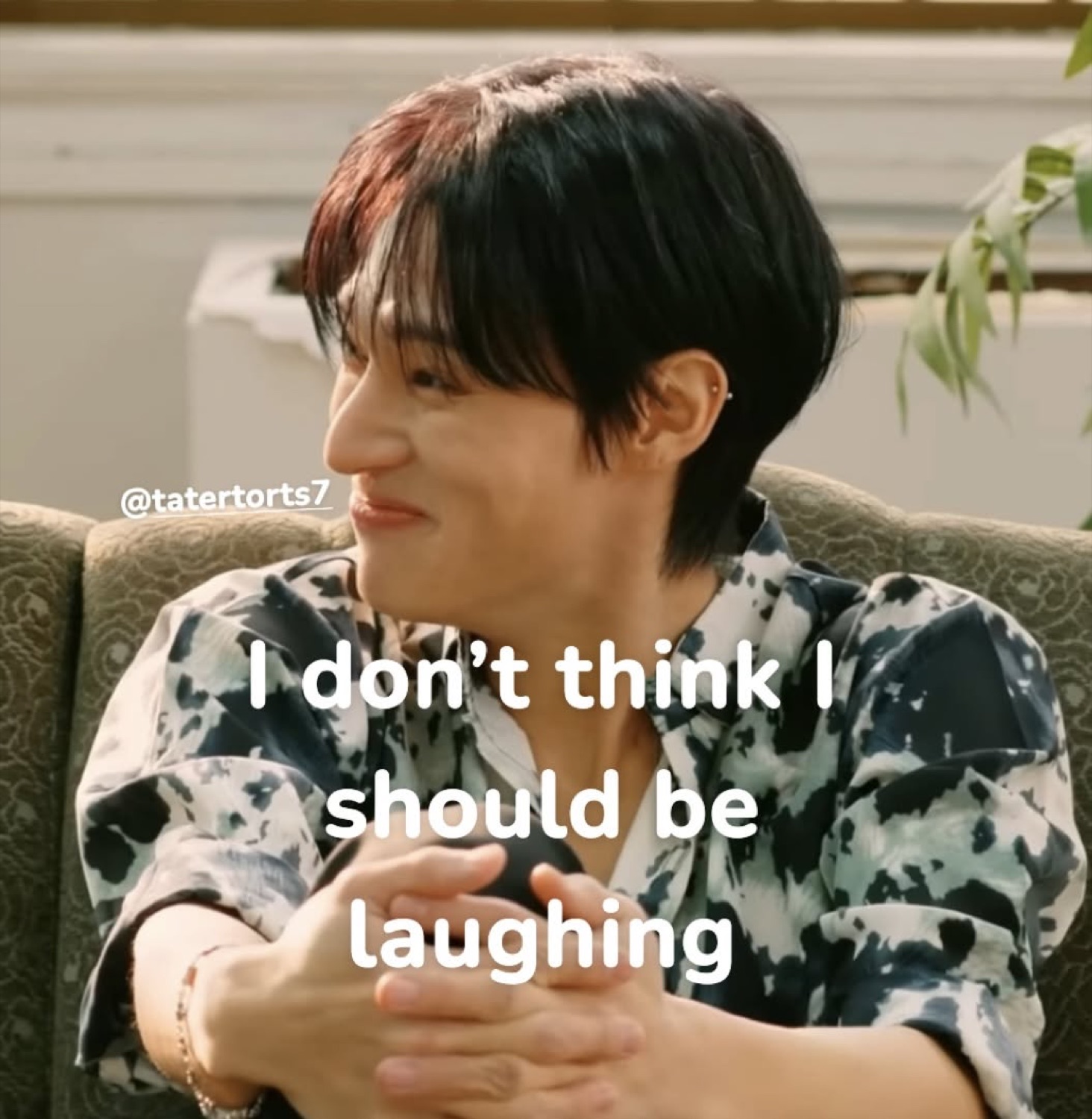Person sitting on a couch smirking while text reads 'I don't think I should be laughing'
