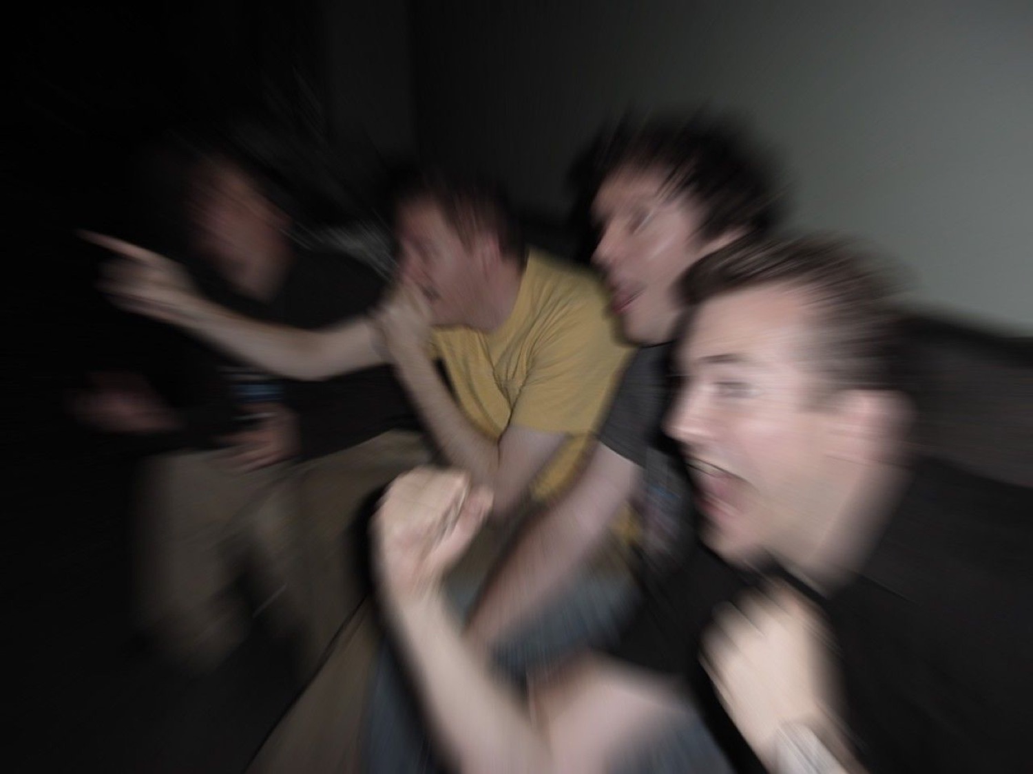 Blurry pack of guys charging forward in a dark room, screaming with excitement