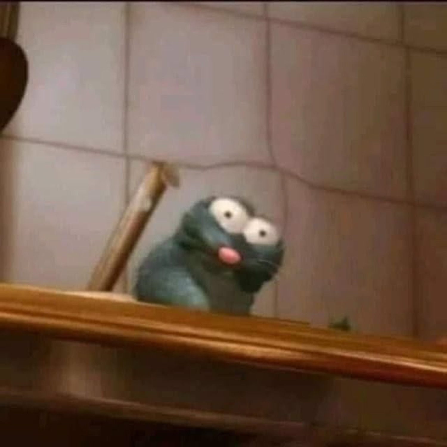 Little grey rat puppet frozen on the stairs with bug eyes and tongue out