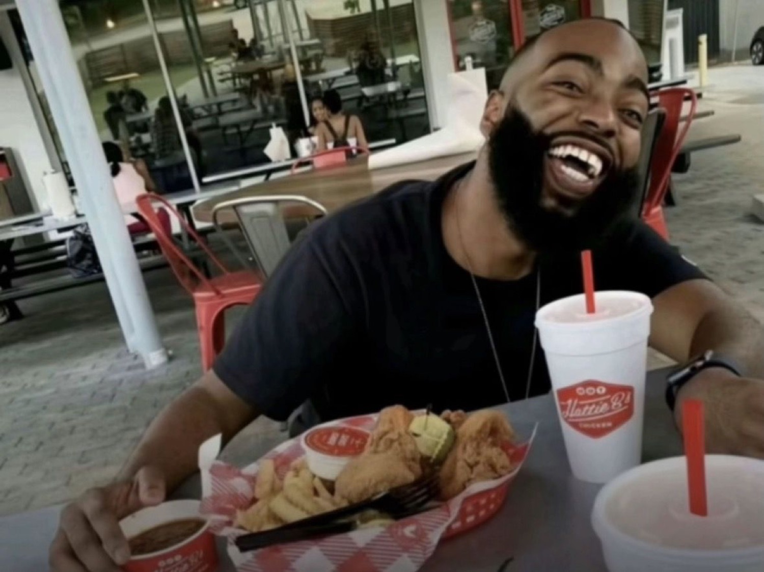 Bearded man with a massive contagious laugh at a restaurant table full of food