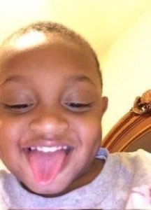 Little kid grinning right up at the camera with their tongue sticking way out