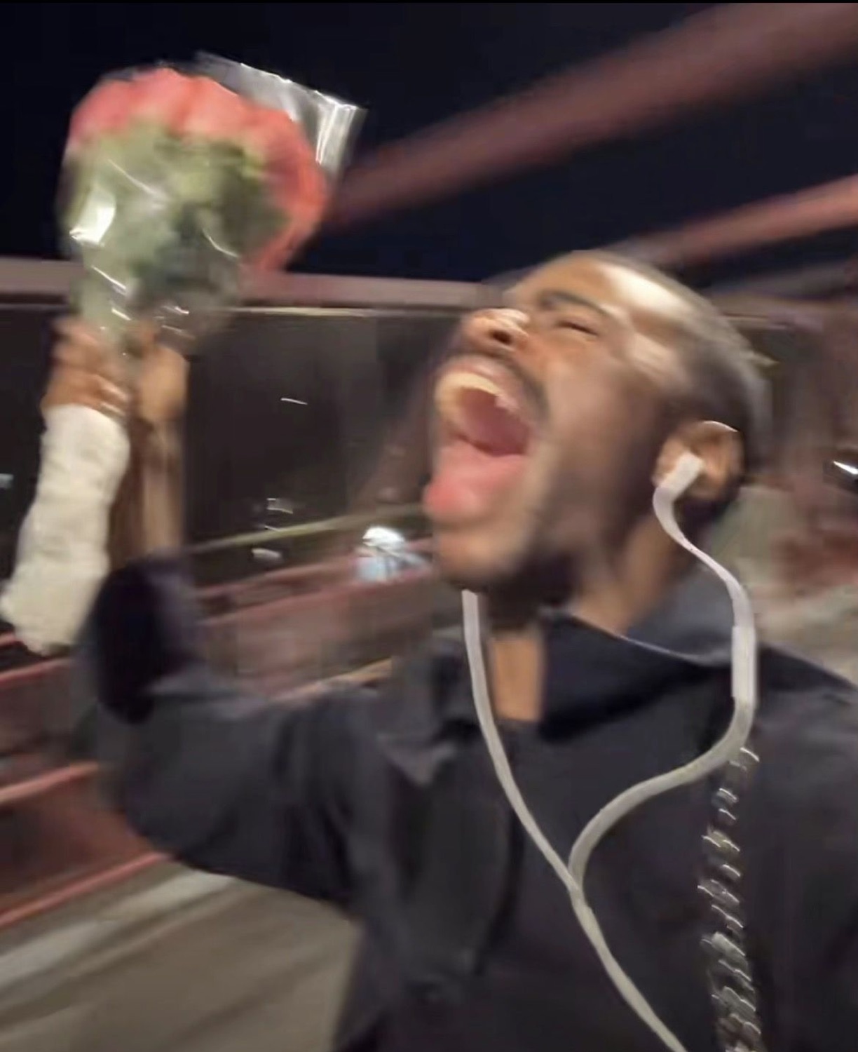 Guy holding up a bouquet of roses, head back mid-scream of pure joy