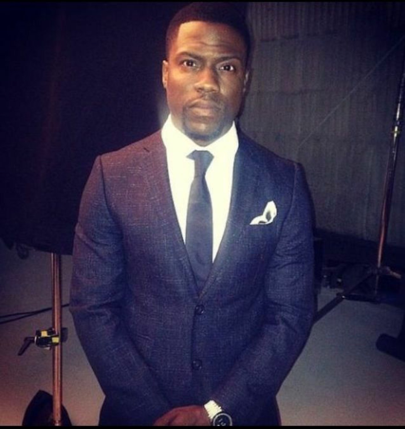 Kevin Hart posing in a sharp navy suit with a cool, deadpan expression