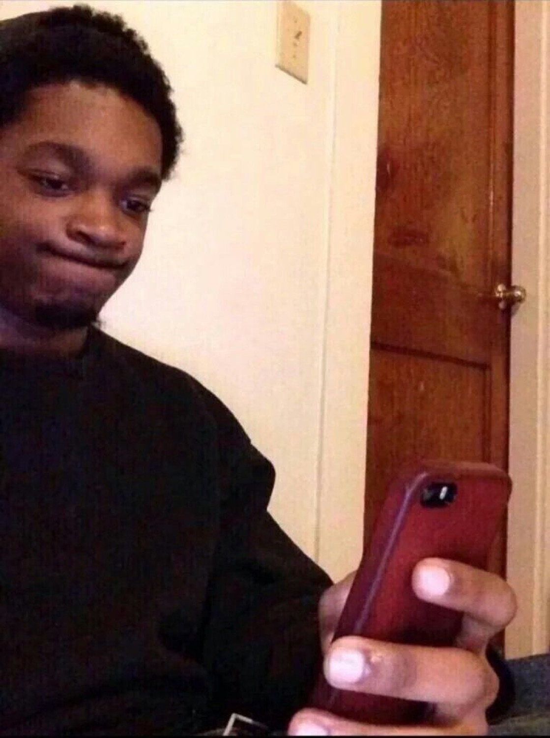Guy glancing down at his phone with a smug, holding-back-a-smirk face