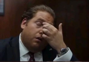 Man in a suit pinching the bridge of his nose in exhausted disbelief