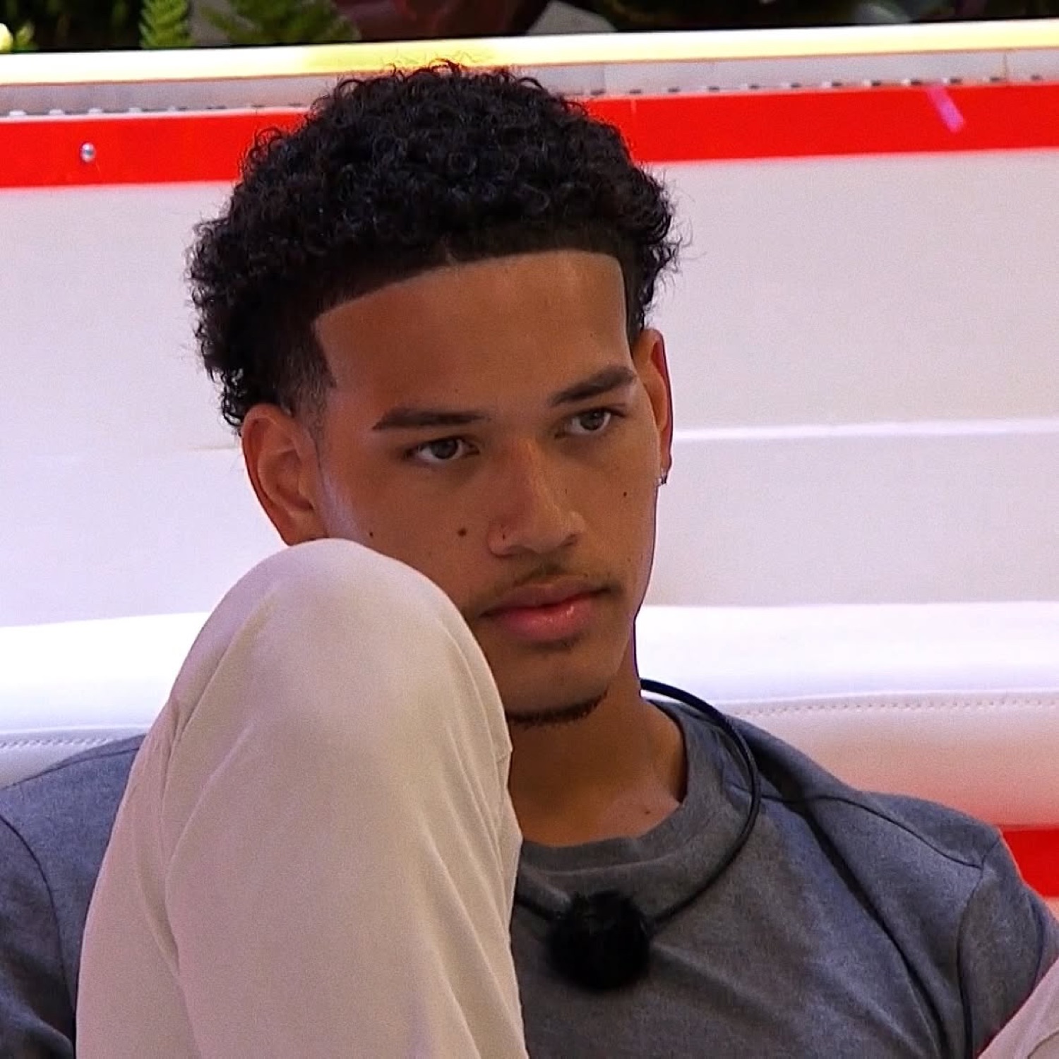 Love Island USA's Corbin hugging his knee with a pensive, unbothered look