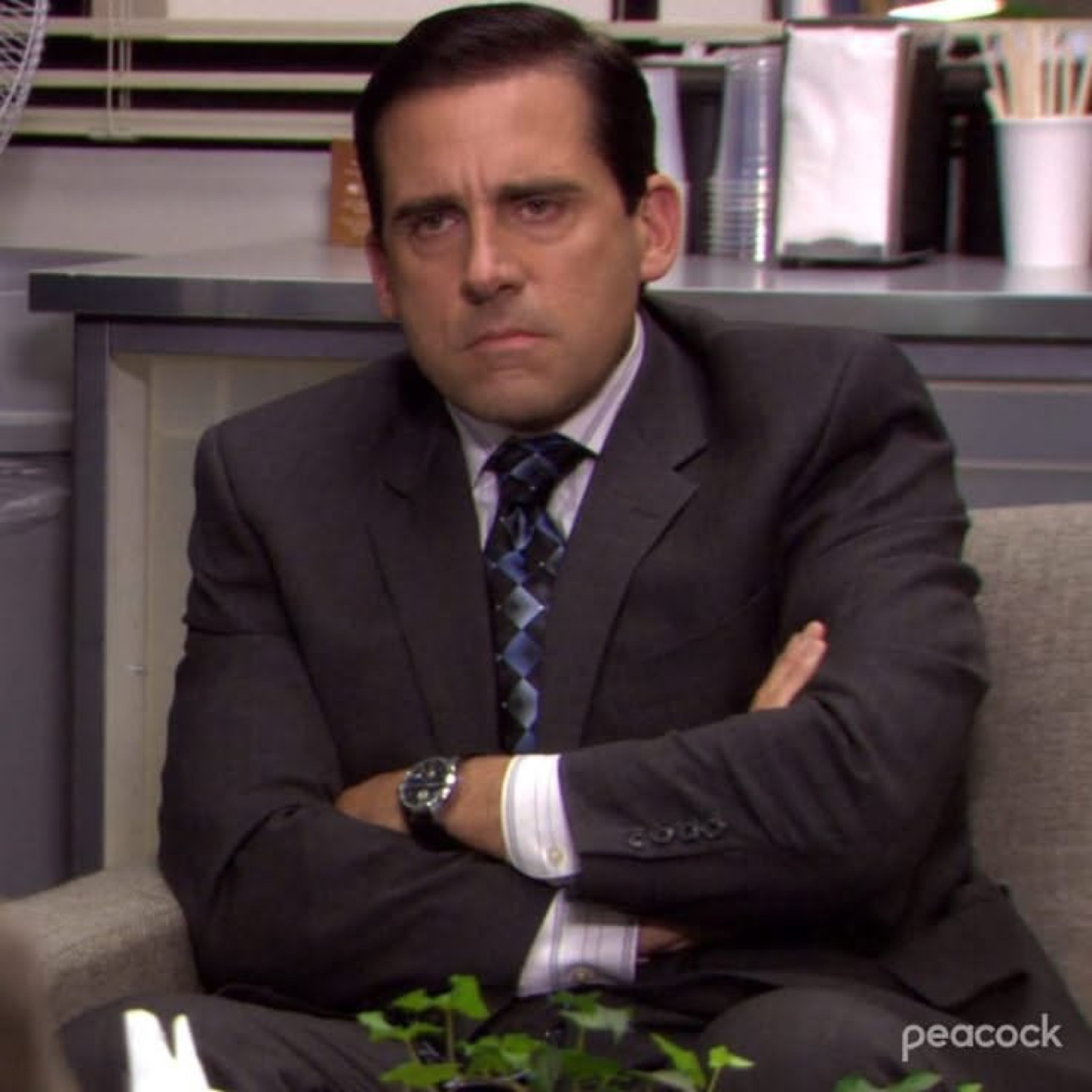Michael Scott slumped in a chair with arms crossed and a grumpy, fed-up frown