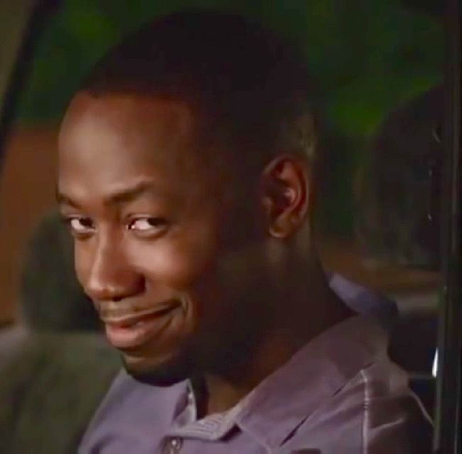 Man glancing sideways from a car with a sheepish, up-to-something smirk