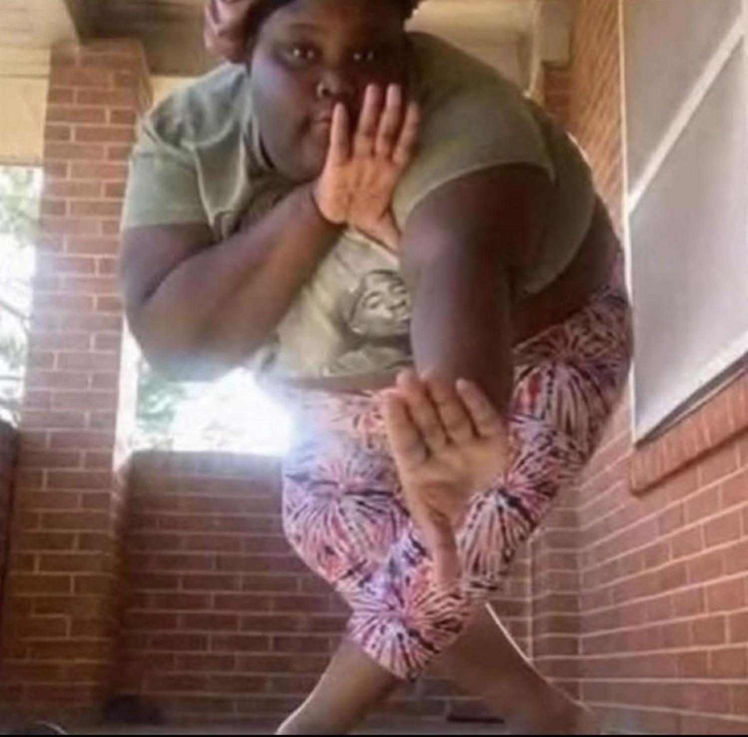 Woman sitting on steps outside with both hands up covering her mouth in shock