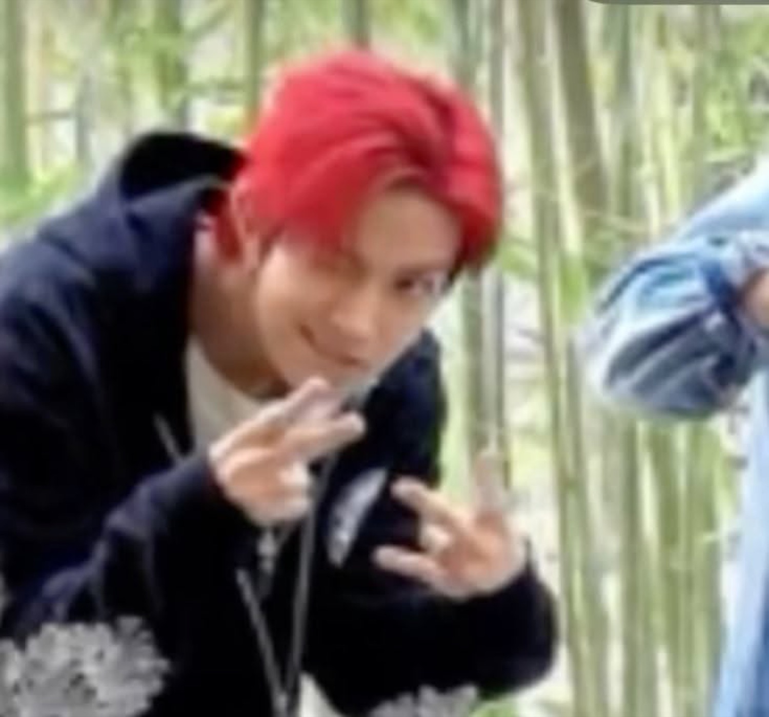 Young man with red hair leaning forward with a cocky smirk, making finger-gun gestures