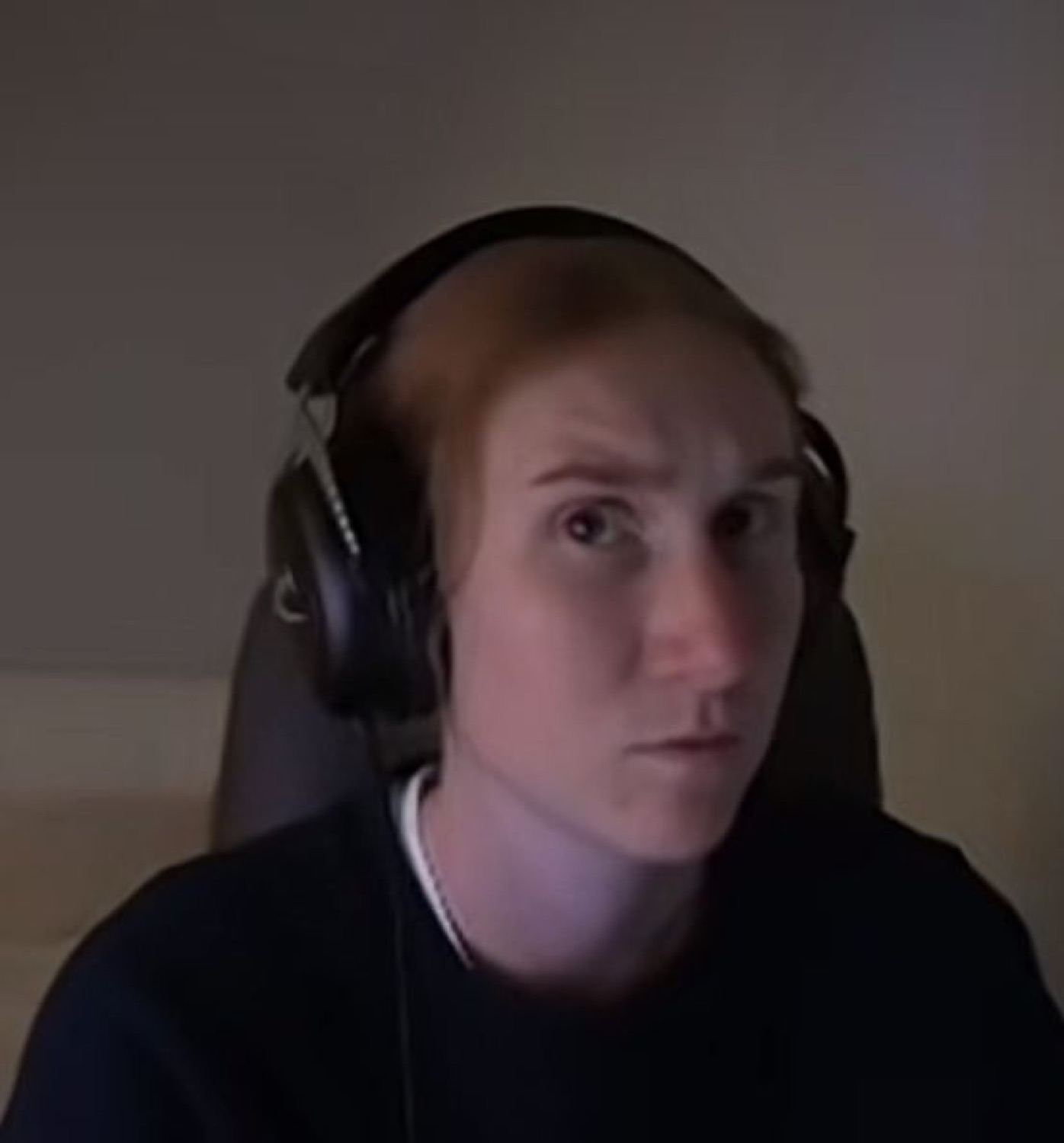 Man in headphones staring at the camera with a tired, deadpan expression