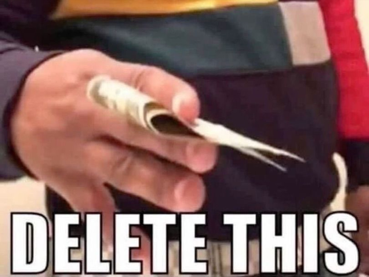 Hand clutching a roll of cash with 'DELETE THIS' text at the bottom