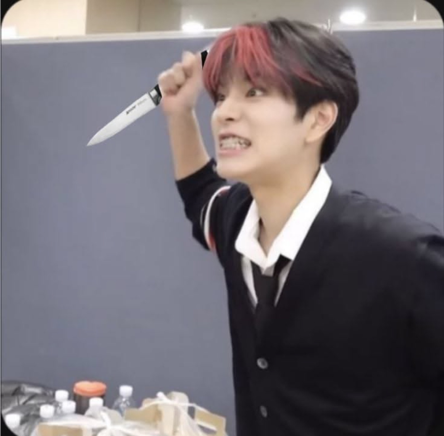 Young man raising a kitchen knife overhead while gritting his teeth
