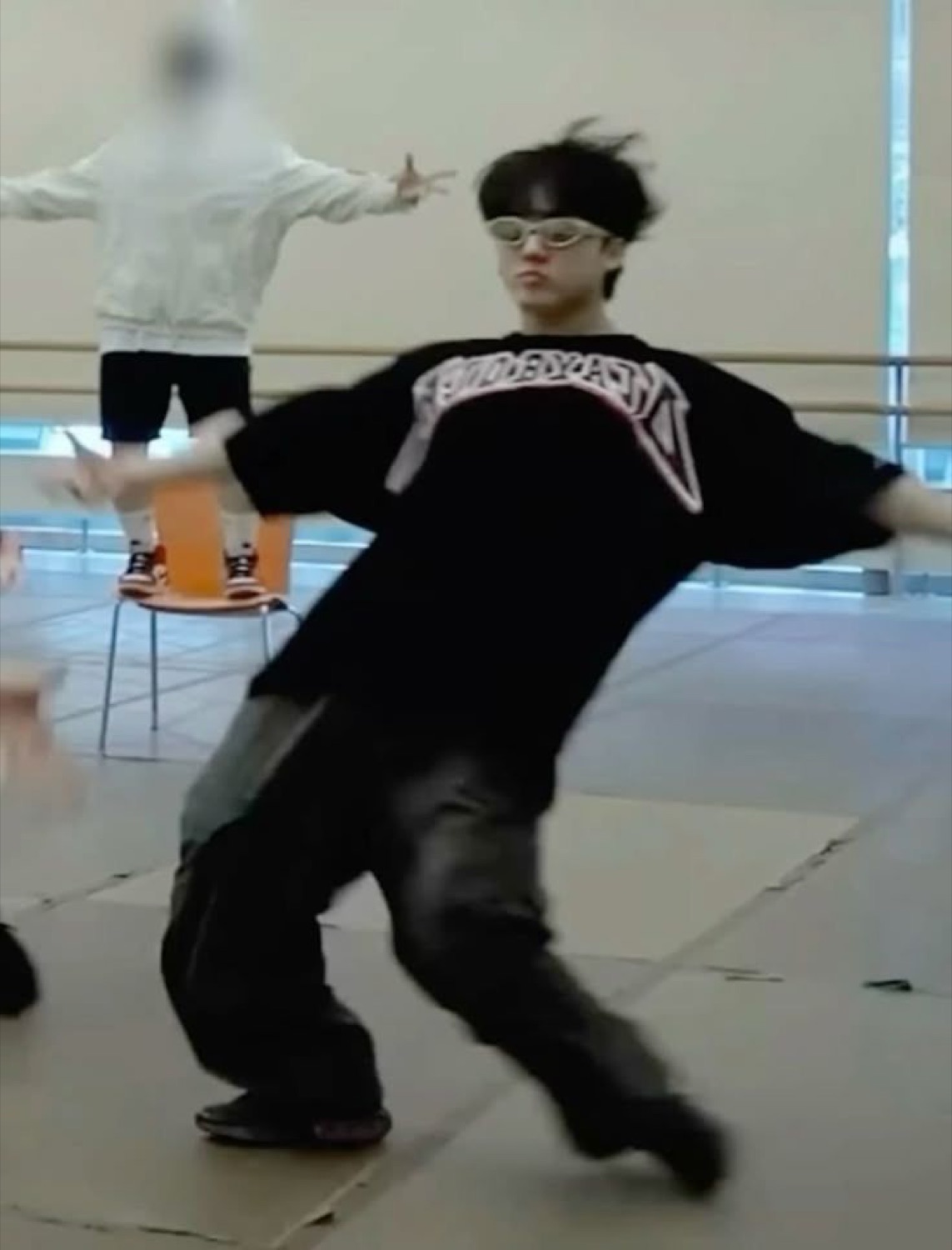 Guy in swim goggles and a baggy black tee busting a dramatic dance move