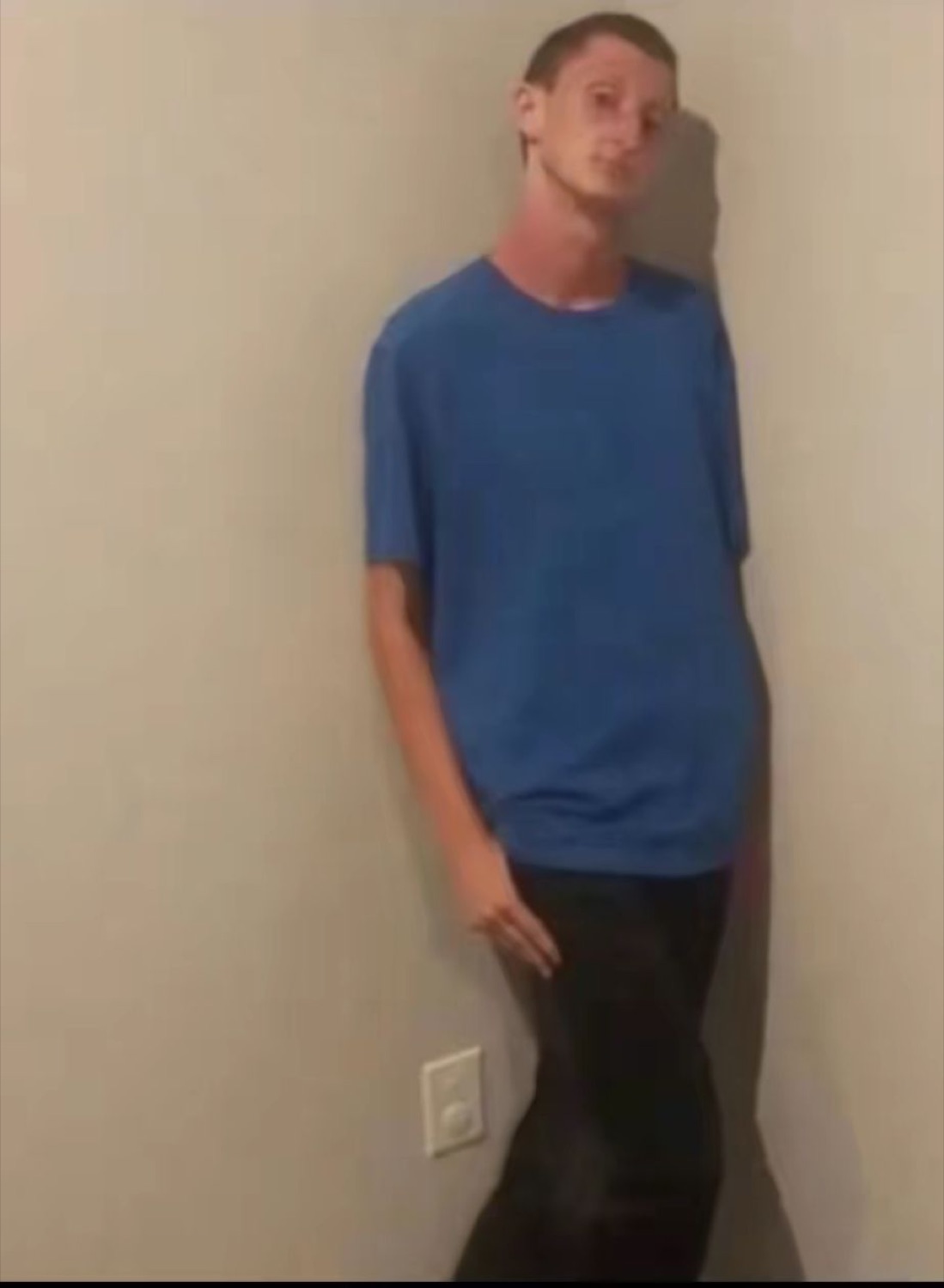 Tall guy leaning against a wall with an awkward stare