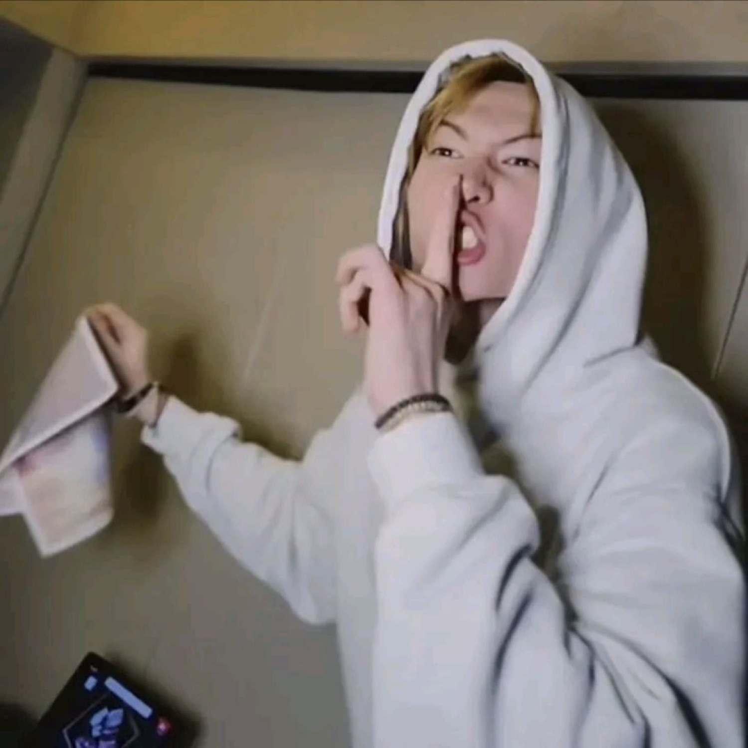 Person in a white hoodie pointing at their nose intensely with an open-mouth expression